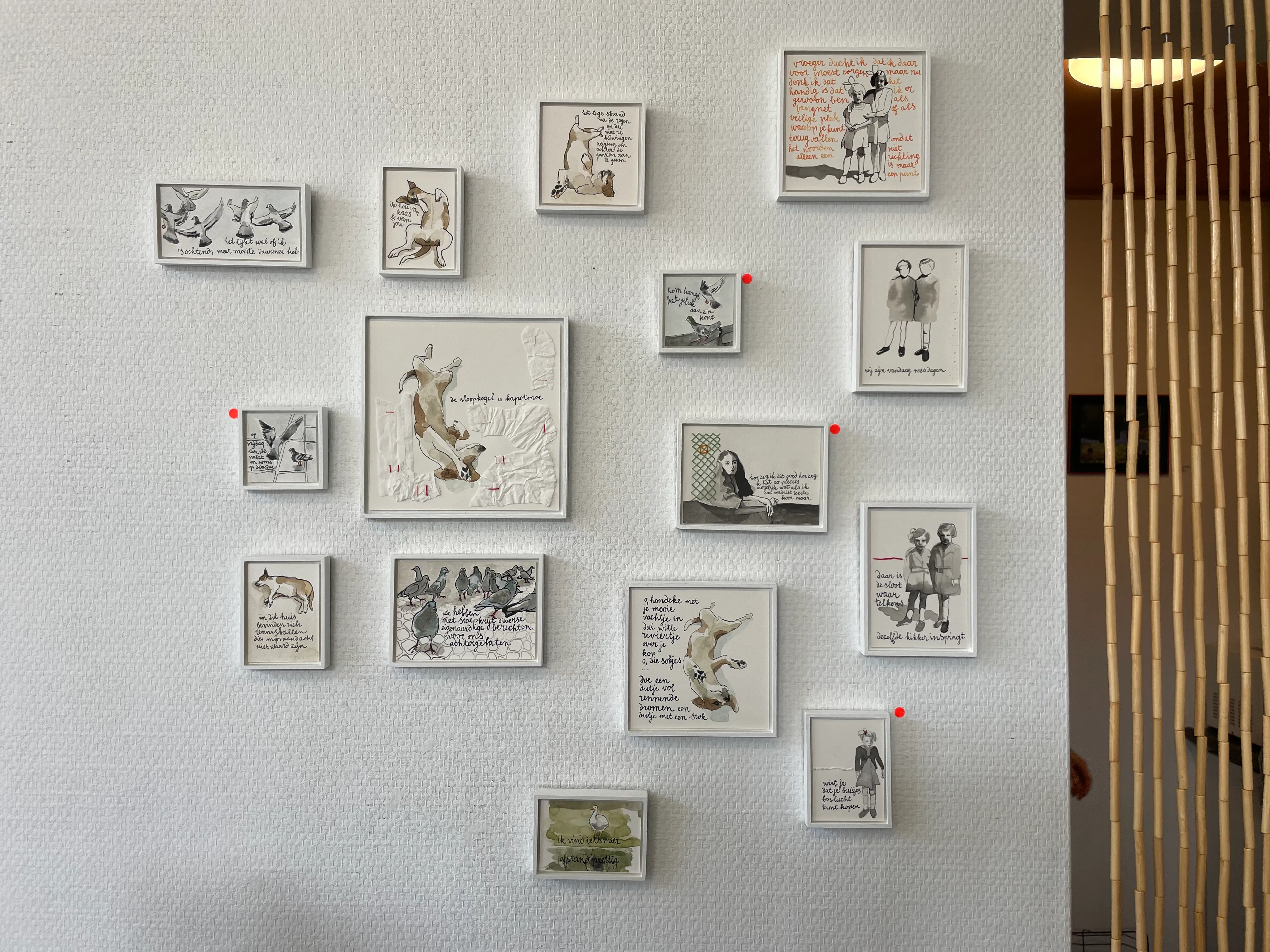 15 werkjes in galerie Arti Shock 15 Werkjes die aan de muur van de galerie hangen, naast een bamboe kralengordijn.